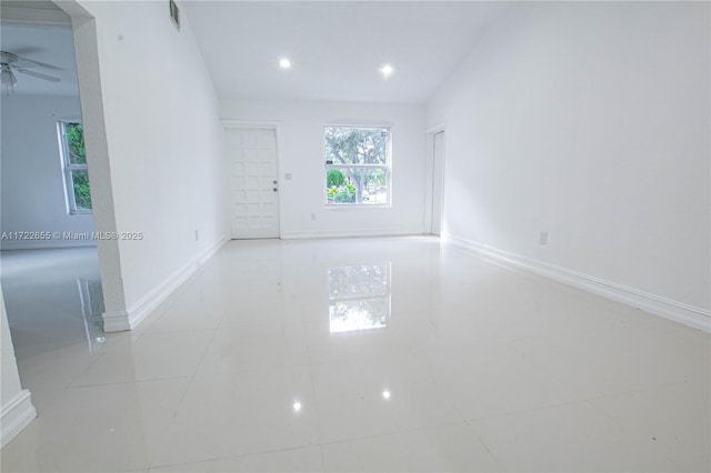 tiled spare room featuring vaulted ceiling and ceiling fan