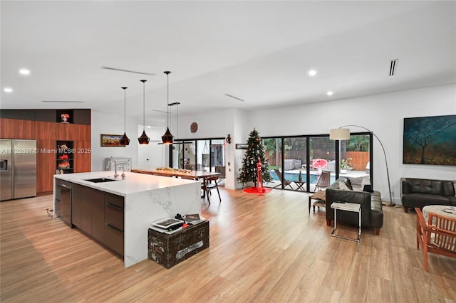 kitchen featuring a spacious island, sink, vaulted ceiling, appliances with stainless steel finishes, and light hardwood / wood-style floors