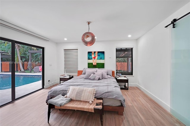 bedroom featuring access to outside, a barn door, and light hardwood / wood-style flooring