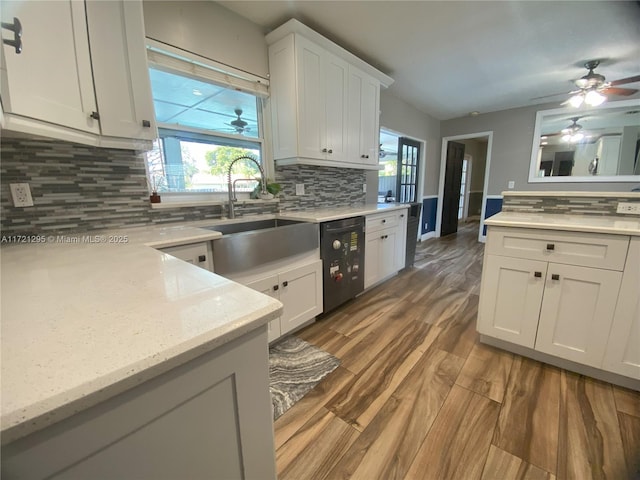 kitchen featuring tasteful backsplash, sink, white cabinets, and black dishwasher