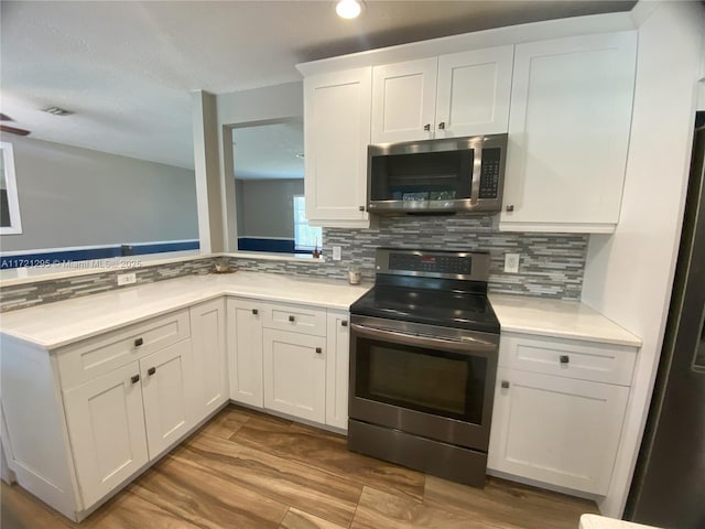 kitchen with light wood-type flooring, white cabinetry, stainless steel appliances, and tasteful backsplash