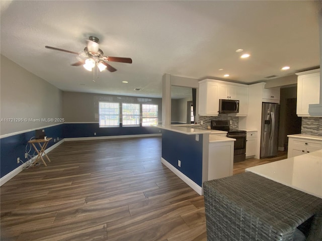 kitchen featuring kitchen peninsula, stainless steel appliances, white cabinetry, and tasteful backsplash