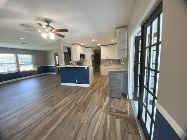 kitchen with ceiling fan, white cabinets, dark hardwood / wood-style floors, decorative backsplash, and a kitchen island