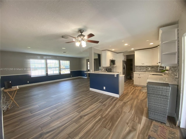 kitchen with dark wood-type flooring, decorative backsplash, ceiling fan, white cabinetry, and stainless steel appliances