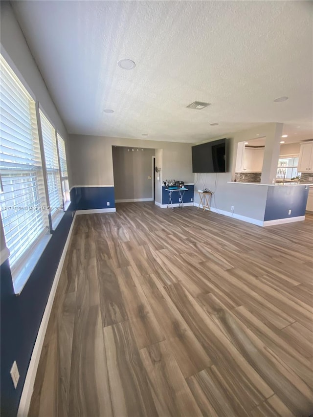 unfurnished living room featuring hardwood / wood-style floors and a textured ceiling