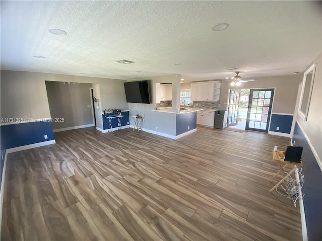 unfurnished living room with hardwood / wood-style floors, a textured ceiling, and ceiling fan