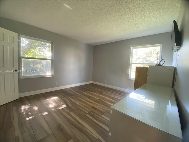 empty room featuring a textured ceiling and dark hardwood / wood-style flooring