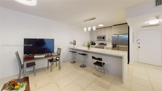 kitchen featuring kitchen peninsula, hanging light fixtures, appliances with stainless steel finishes, and a breakfast bar area