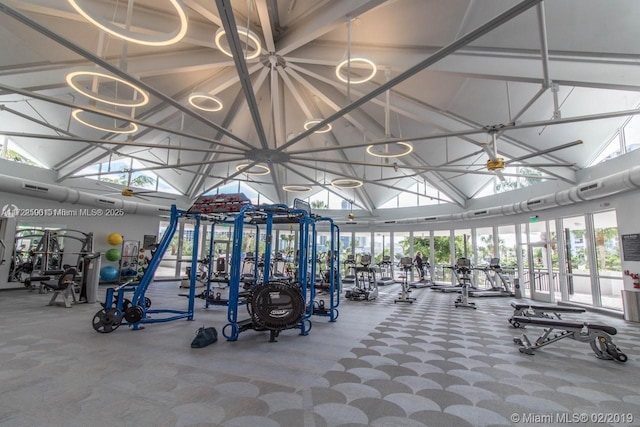 exercise room with ceiling fan and high vaulted ceiling