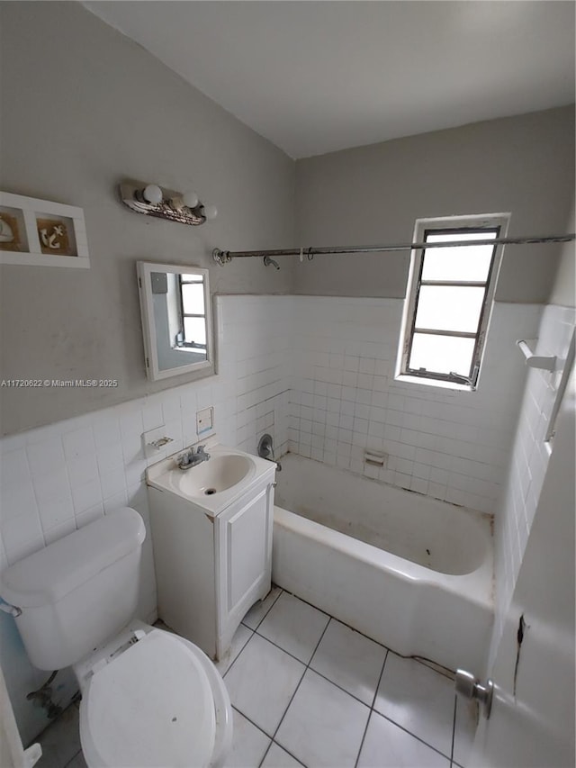 bathroom featuring tile patterned floors, toilet, tile walls, vanity, and a washtub