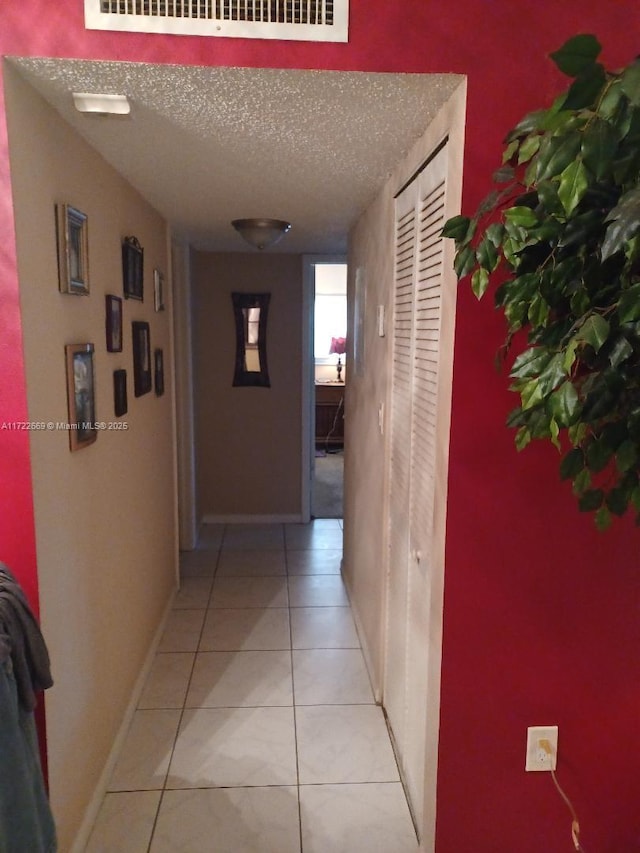 corridor with light tile patterned floors and a textured ceiling