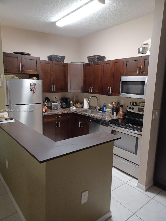 kitchen with light tile patterned floors, a textured ceiling, stainless steel appliances, and sink