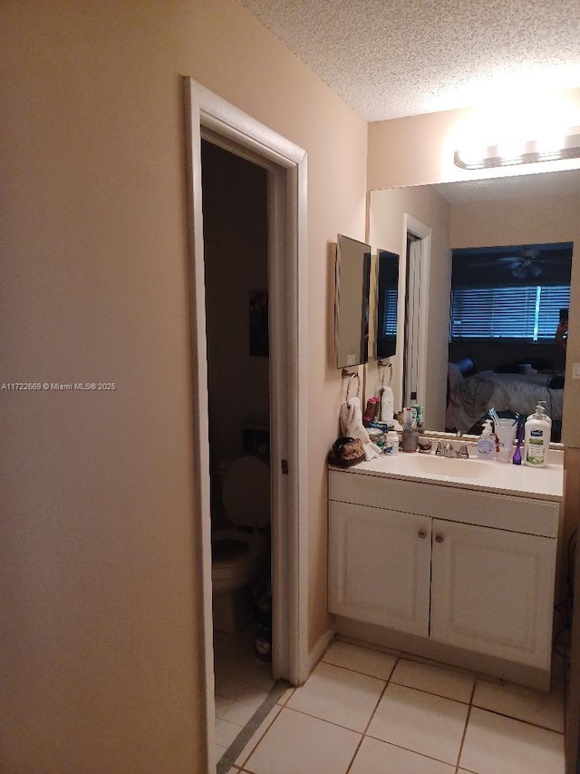 bathroom featuring tile patterned flooring, vanity, a textured ceiling, and toilet