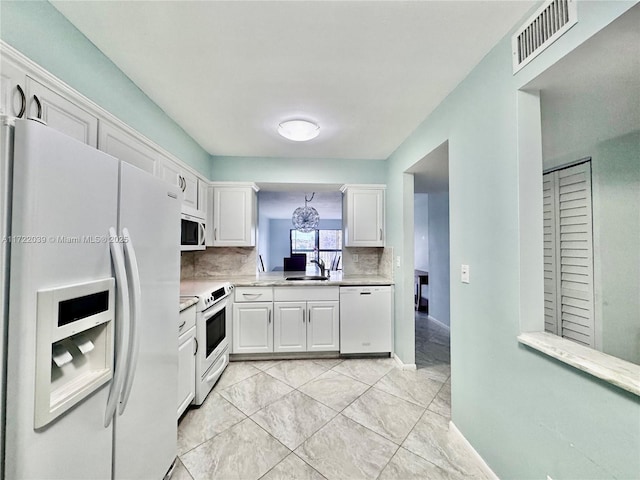 kitchen with white cabinetry, sink, and white appliances