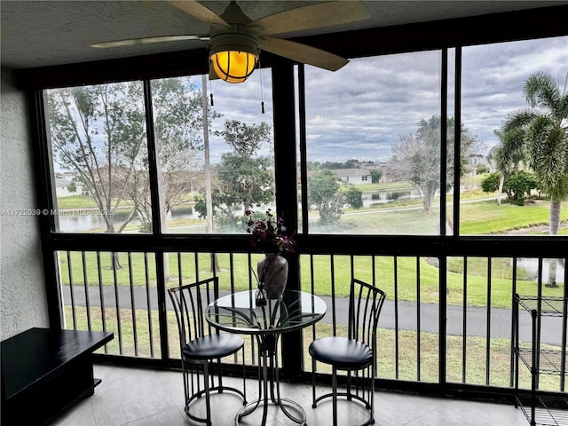 sunroom featuring a water view and ceiling fan