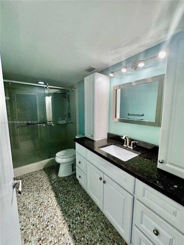 bathroom featuring vanity, toilet, tile patterned flooring, and a shower with door