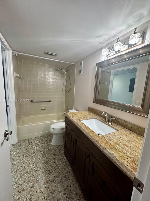 full bathroom featuring tiled shower / bath, vanity, and toilet