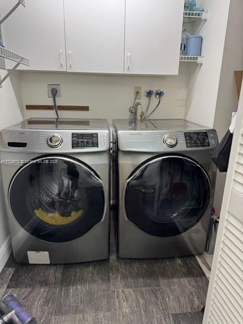 clothes washing area with cabinets and washing machine and clothes dryer