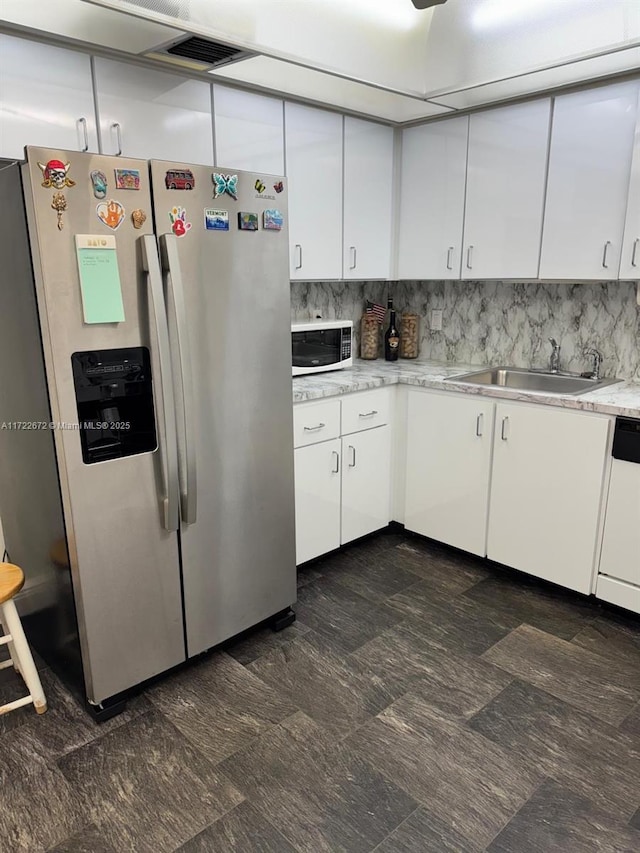 kitchen with white cabinets, stainless steel fridge with ice dispenser, white dishwasher, and sink