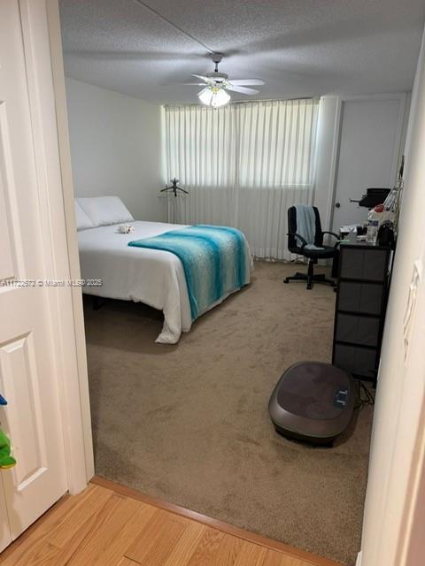 bedroom featuring ceiling fan, light hardwood / wood-style flooring, and a textured ceiling