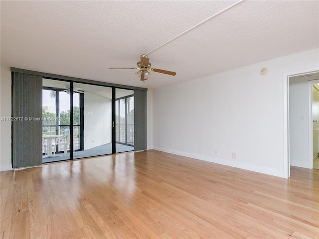 unfurnished room with floor to ceiling windows, ceiling fan, light hardwood / wood-style floors, and a textured ceiling
