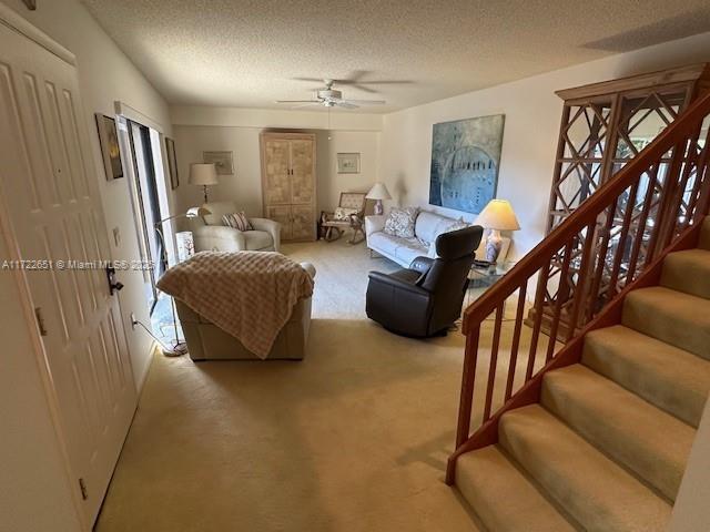 carpeted living room featuring a textured ceiling and ceiling fan