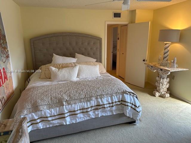 carpeted bedroom with ceiling fan and visible vents