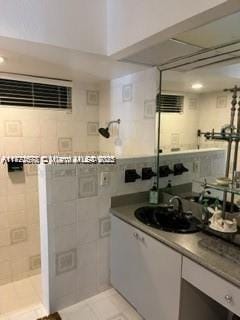 bathroom featuring tile patterned flooring, vanity, and walk in shower