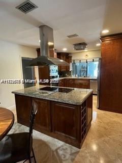 kitchen with black electric stovetop, dark brown cabinets, and island range hood