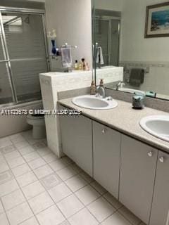 full bathroom featuring tile patterned flooring, vanity, shower / bath combination with glass door, and toilet