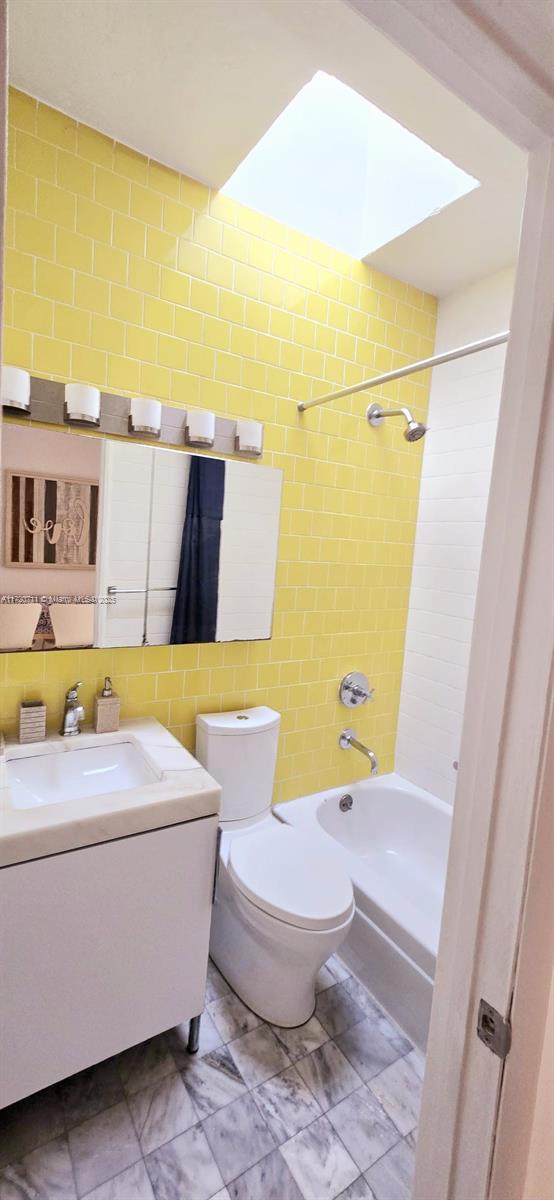 full bathroom featuring vanity, tiled shower / bath combo, and toilet