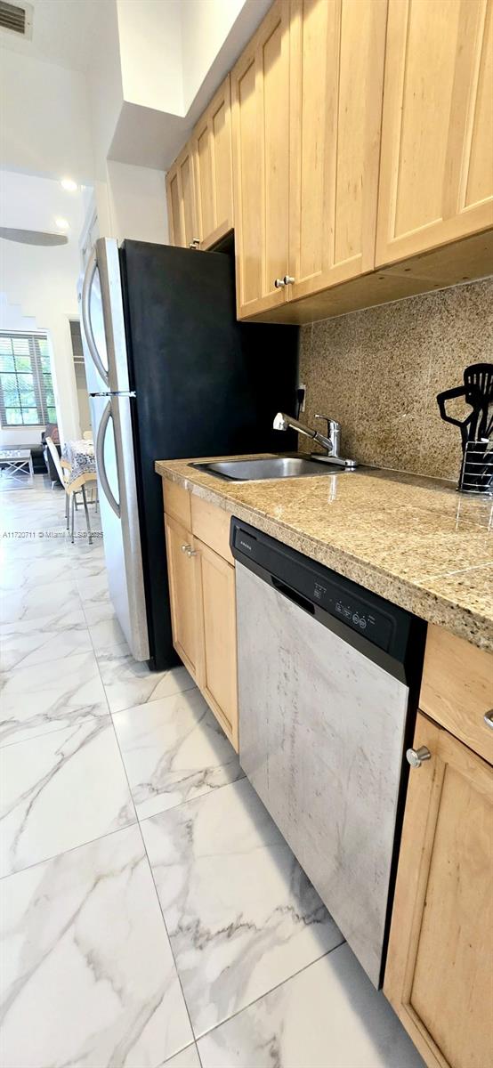 kitchen with dishwasher, light brown cabinetry, backsplash, and sink