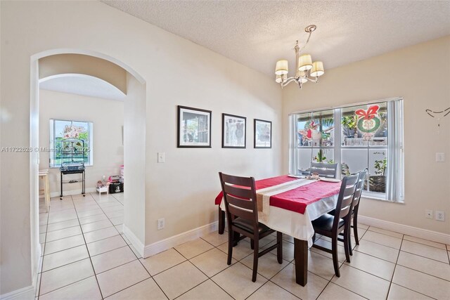 dining room featuring a textured ceiling, a notable chandelier, and light tile patterned floors