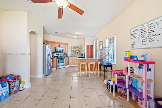 kitchen featuring light tile patterned floors, sink, a breakfast bar, stainless steel appliances, and a textured ceiling