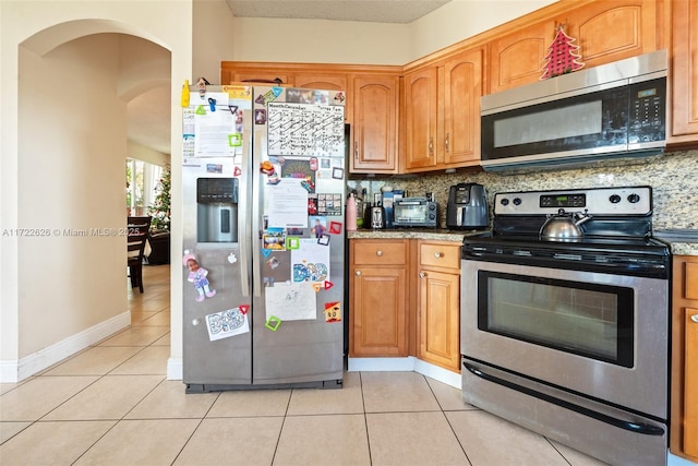 kitchen featuring appliances with stainless steel finishes, tasteful backsplash, and light tile patterned floors