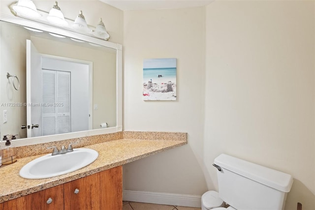 bathroom with toilet, vanity, and tile patterned floors