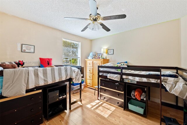 bedroom with ceiling fan, light hardwood / wood-style floors, and a textured ceiling