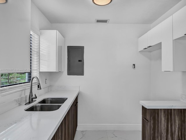 kitchen with dark brown cabinetry, electric panel, white cabinetry, and sink