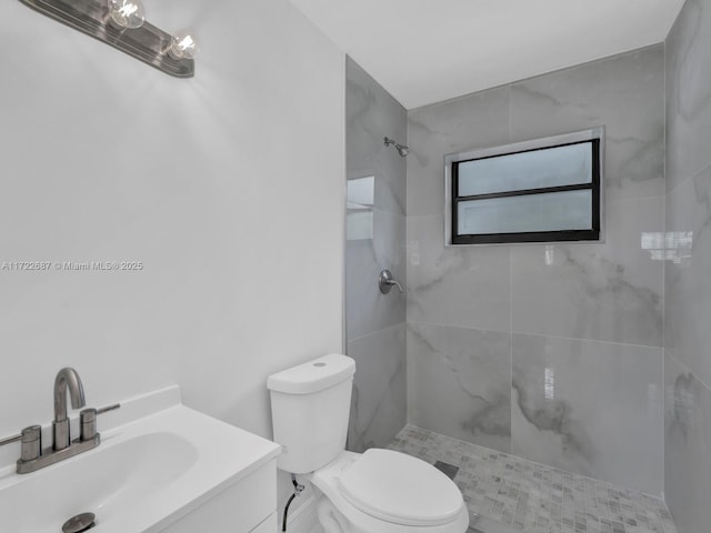 bathroom featuring a tile shower, vanity, and toilet