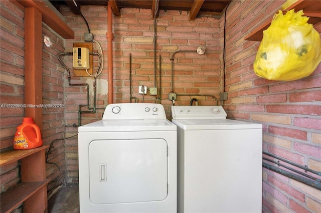 washroom featuring washer and dryer and brick wall