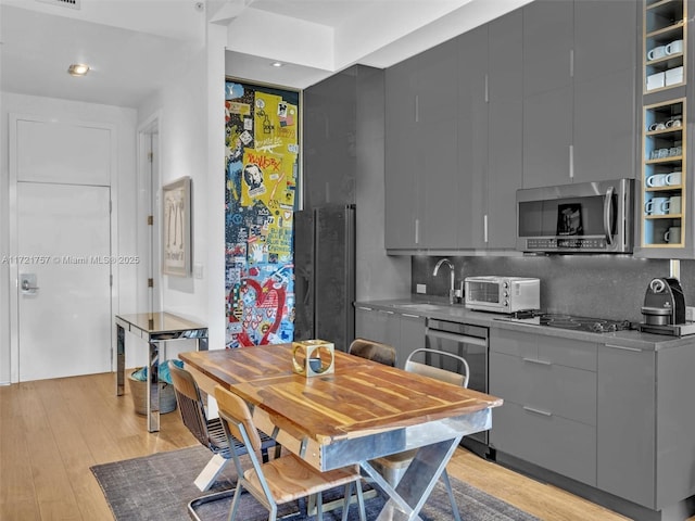 kitchen with sink, gas stovetop, gray cabinets, dishwasher, and light hardwood / wood-style floors