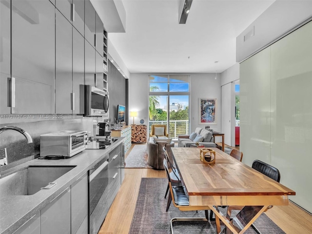 kitchen featuring expansive windows, sink, decorative backsplash, and light wood-type flooring