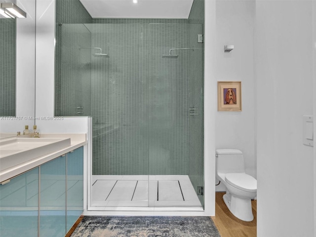 bathroom featuring vanity, wood-type flooring, toilet, and tiled shower