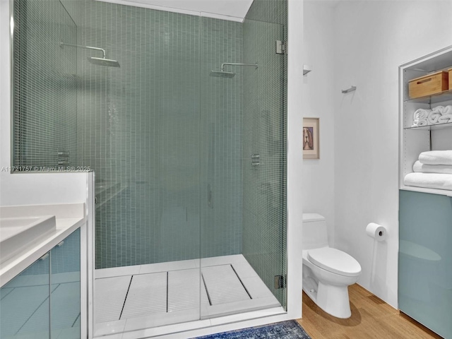 bathroom featuring wood-type flooring, toilet, and a tile shower