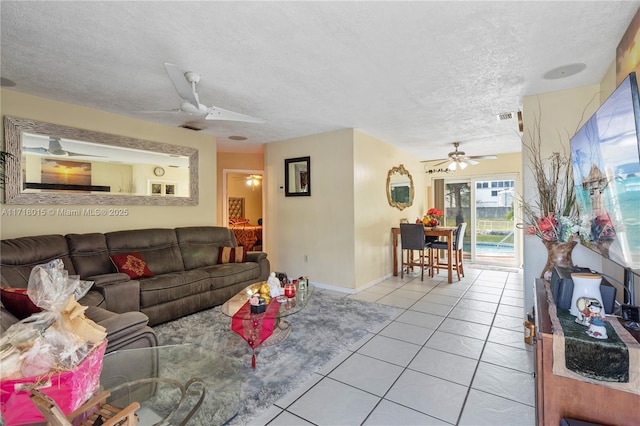 living room with ceiling fan, light tile patterned floors, and a textured ceiling