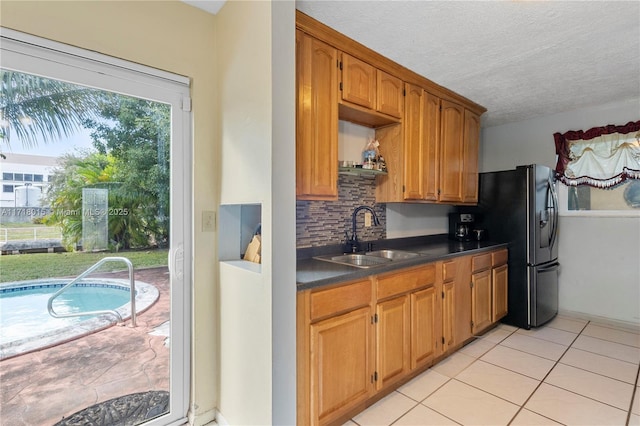 kitchen with backsplash, a textured ceiling, sink, light tile patterned floors, and stainless steel fridge with ice dispenser