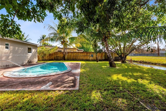 view of pool with a yard and a water view