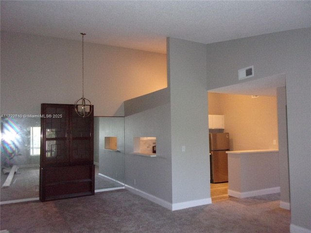 empty room with an inviting chandelier, vaulted ceiling, and carpet flooring