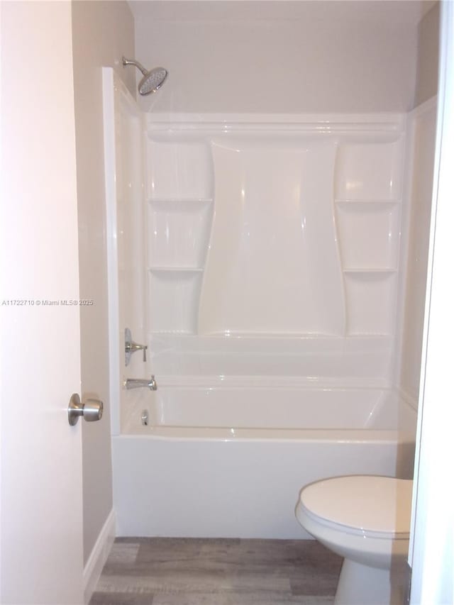 bathroom with shower / bathing tub combination, hardwood / wood-style flooring, and toilet