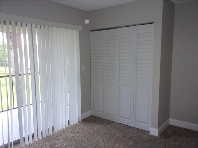 unfurnished bedroom featuring a closet, multiple windows, and dark carpet